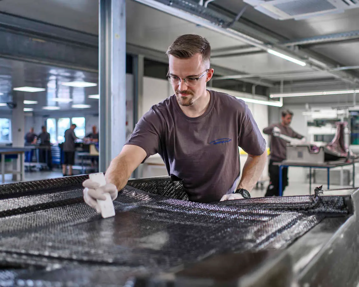 Ein Mitarbeiter der Weinkauf GmbH bearbeitet in detailierter Handarbeit ein Carbon-Bauteil